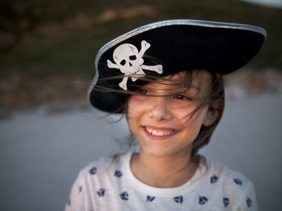Portrait of smiling girl wearing pirate's hat on the beach