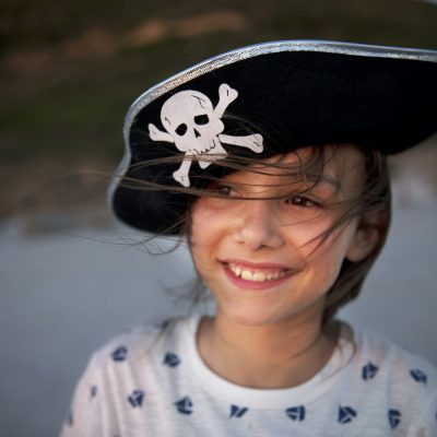 Portrait of smiling girl wearing pirate's hat on the beach